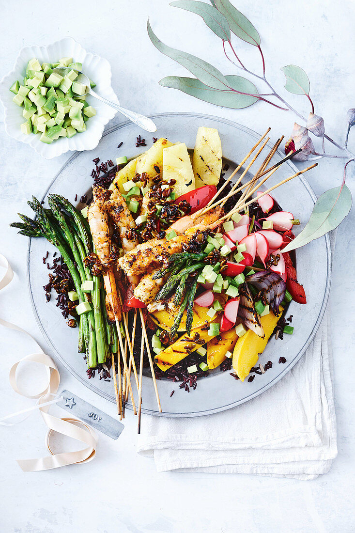 A colourful grill platter with shrimps, fruits, vegetables and black rice