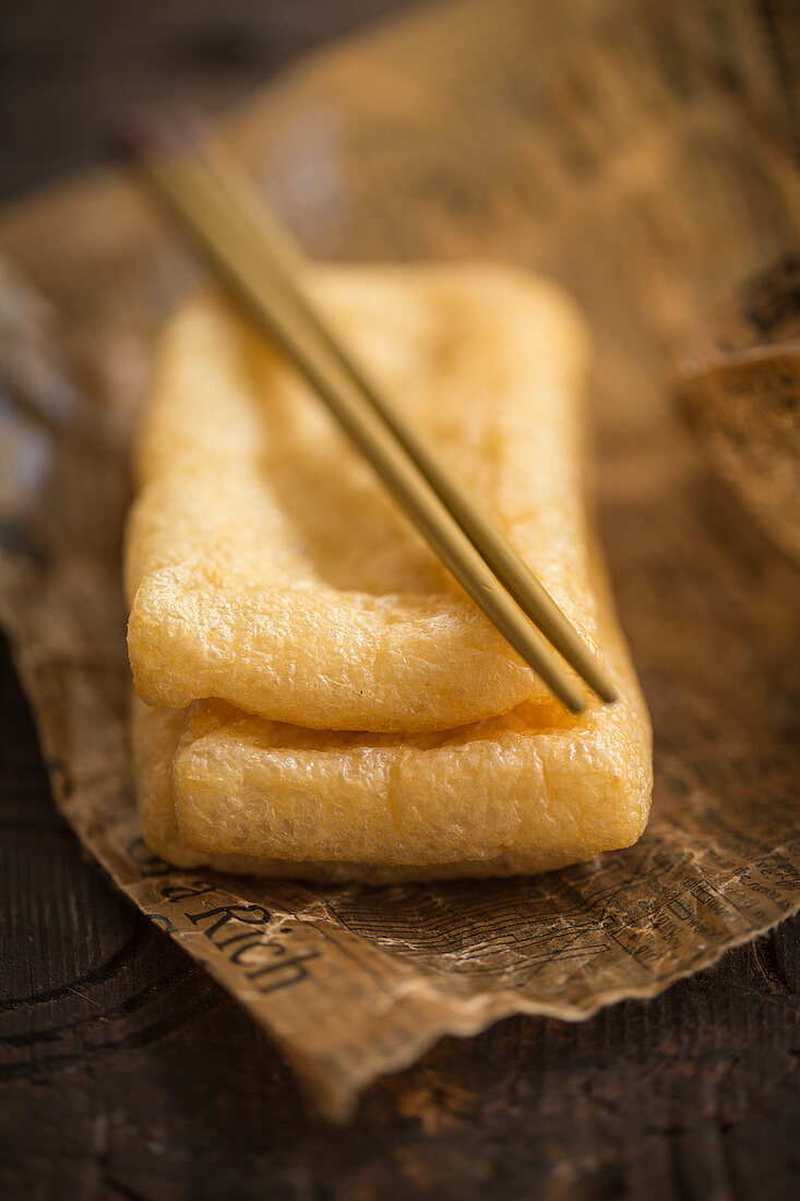 Fried tofu with chopsticks on paper (Asia)