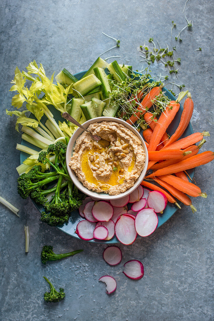 Hausgemachter Hummus mit Olivenöl, Pinienkernen und rohem Gemüse zum Dippen