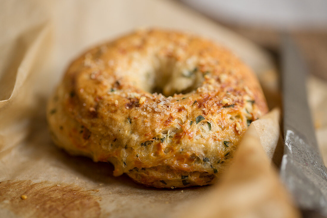 Ein hausgemachter Bagel auf Backpapier (Nahaufnahme)