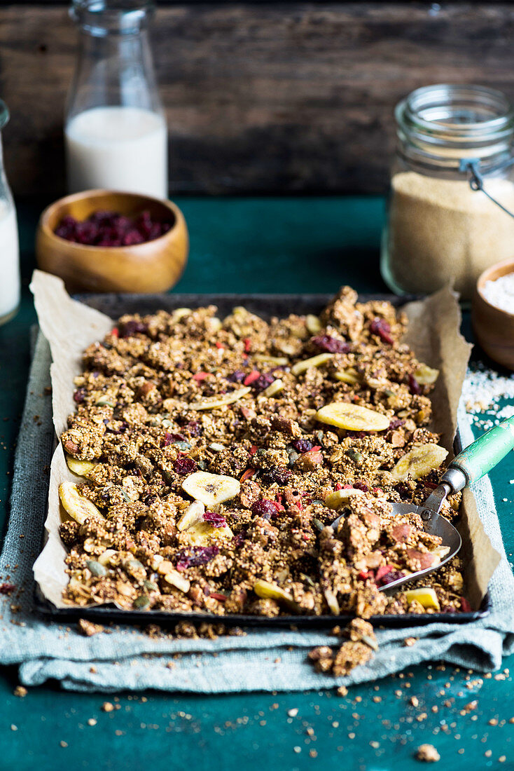 Amaranth and nutbutter granola with dried fruit on a baking tray (vegan)