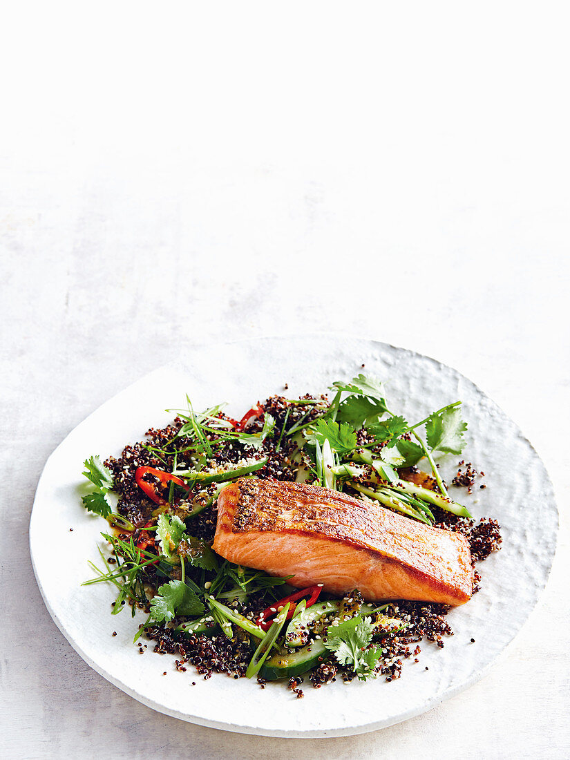 Knusprig gebratener Lachs auf schwarzem Quinoa-Gurkensalat