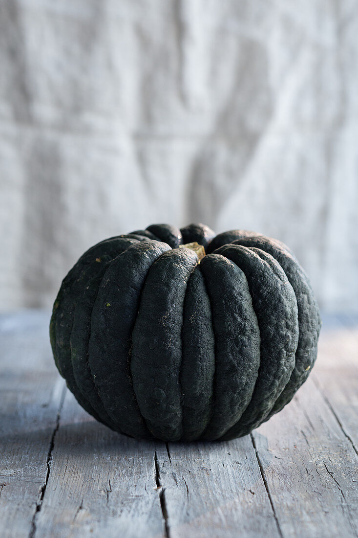 A dark green pumpkin on a wooden table