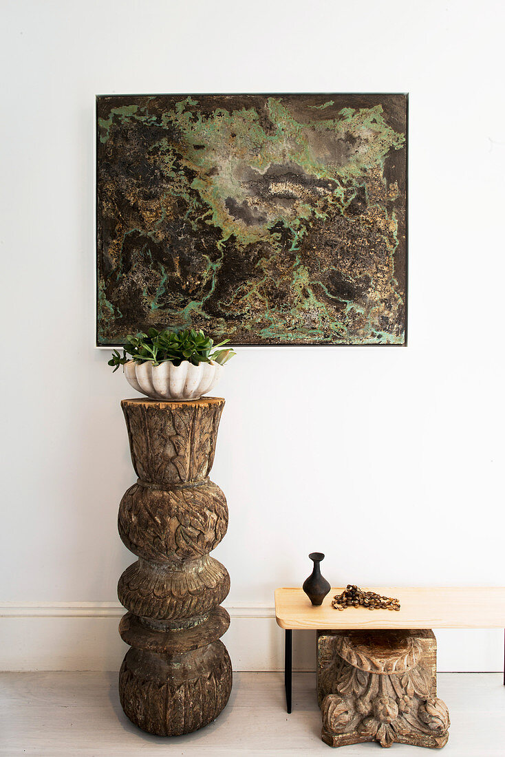 Plant bowl on wooden sculpture, picture in white corridor above
