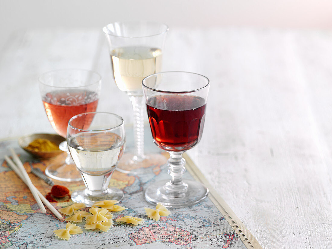 Four different wines in glasses standing on a world map