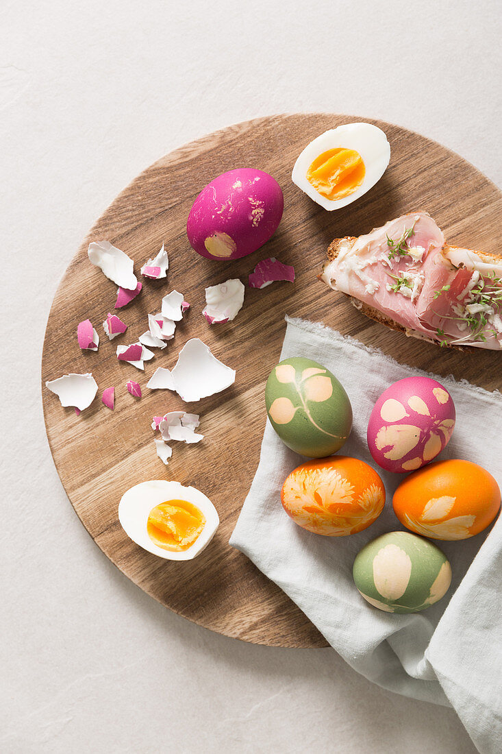 Easter eggs and open ham sandwiches on a wooden plates