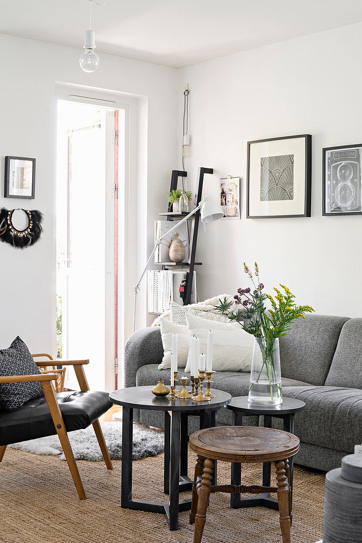 Coffeetable, Lederstuhl und graues Polstersofa im Wohnzimmer mit weißer Wand