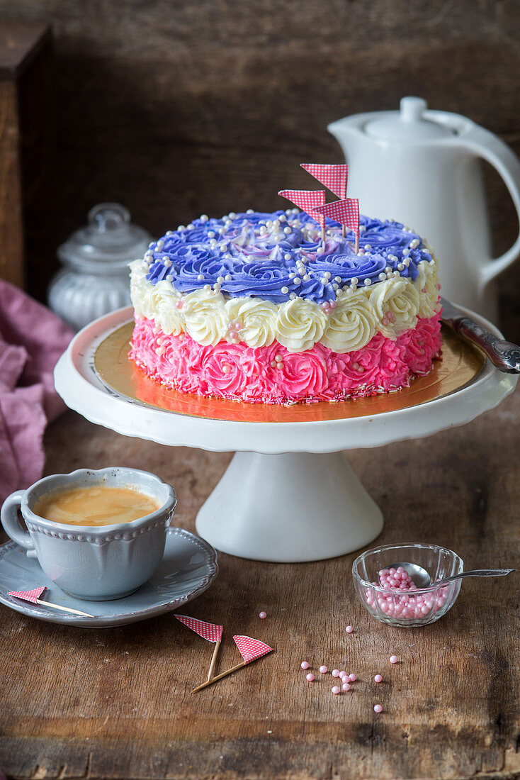 A tri-coloured buttercream cake on a cake stand