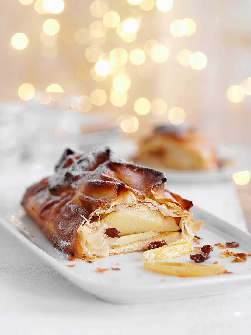 Apple strudel with cinnamon and raisins, sliced on a serving plate