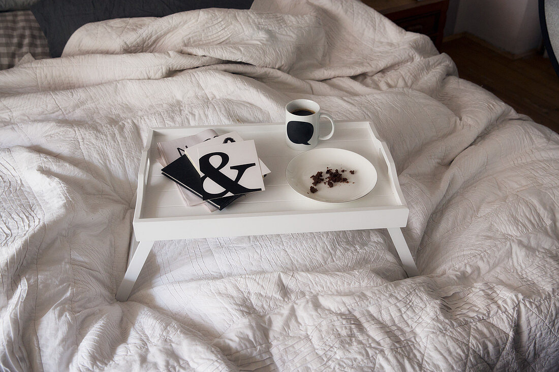 Black and white utensils on a breakfast tray on a bed