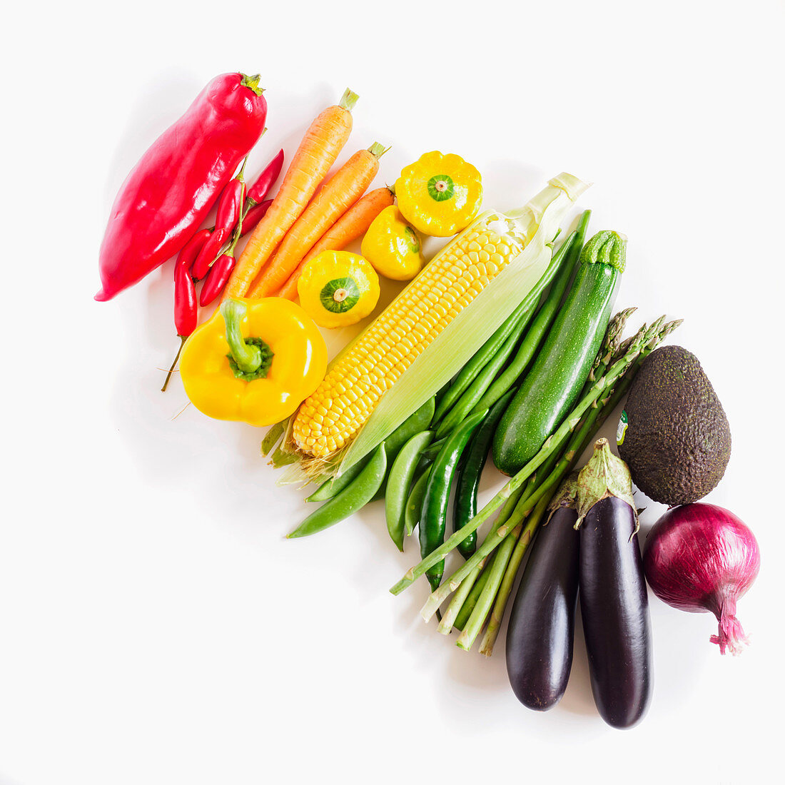 Fresh vegetables arranged by colour on a white background