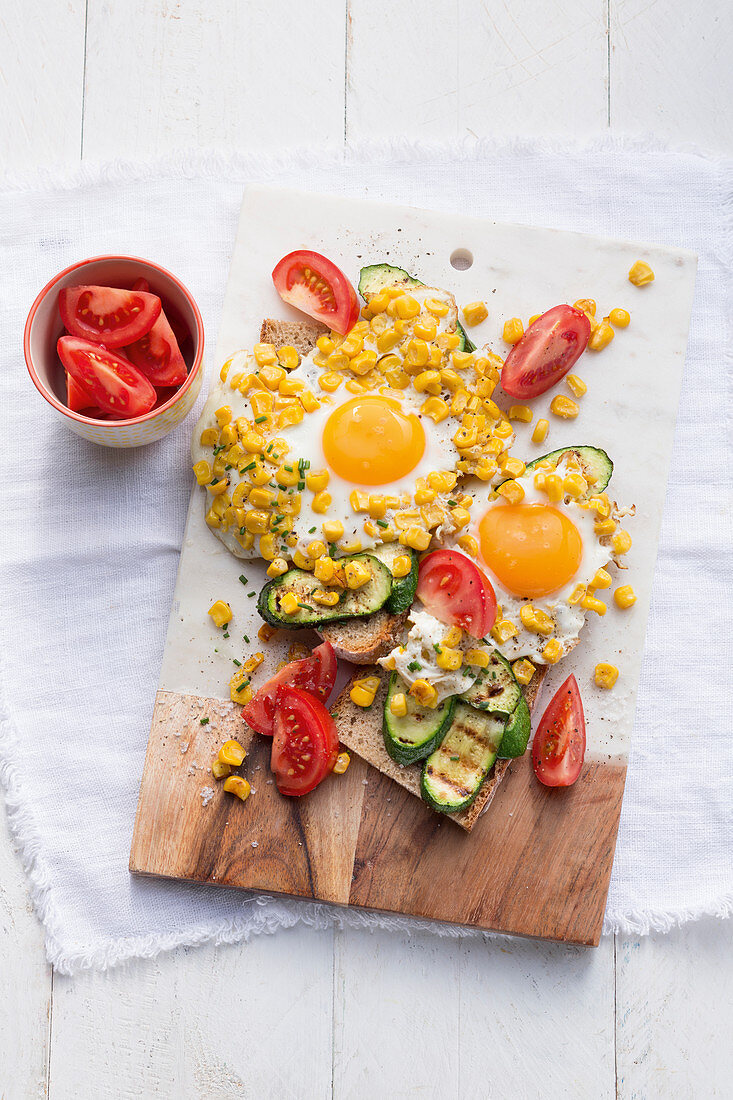 Bread topped with vegetables and fried eggs