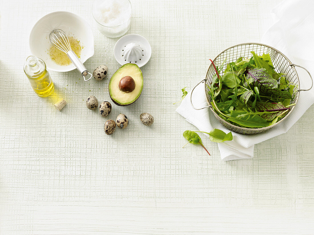 Salad ingredients: lettuce, dressing, avocado and quail eggs