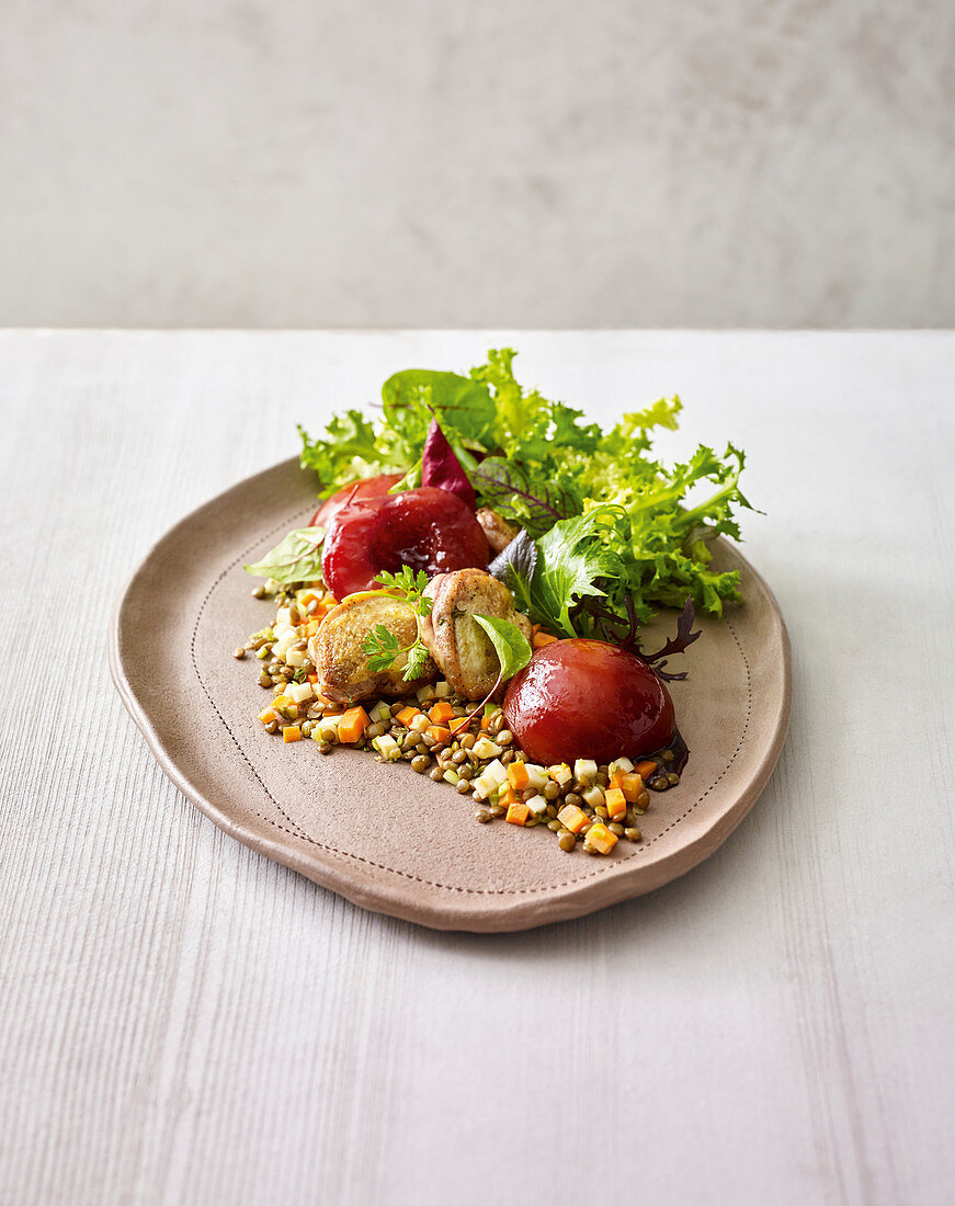 Fried quail breast with pickled peaches on a bed of lentils