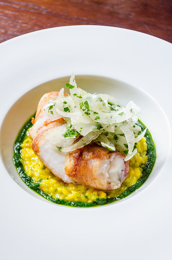 Sea bass fish fillet fricasee on a saffron risotto with wild fennel, basil, chilli