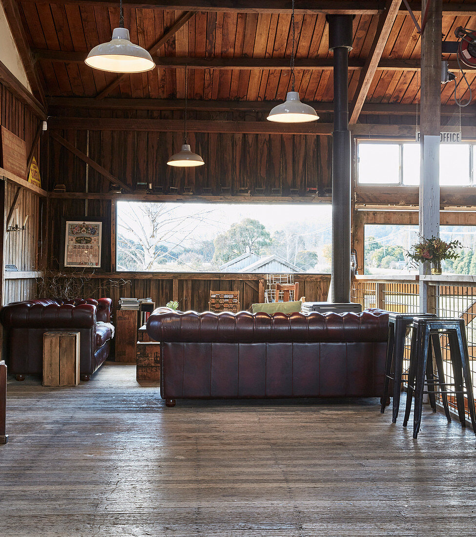 Vintage leather suite and bar stool in open living room with wooden paneling