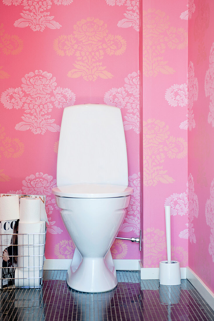 Toilet against pink wallpaper with floral pattern