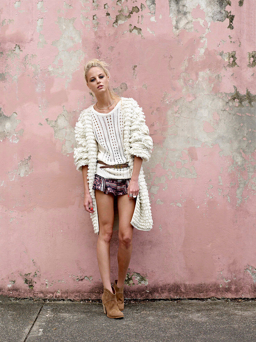 A young blonde woman wearing a white jumper, a matching cardigan and shorts