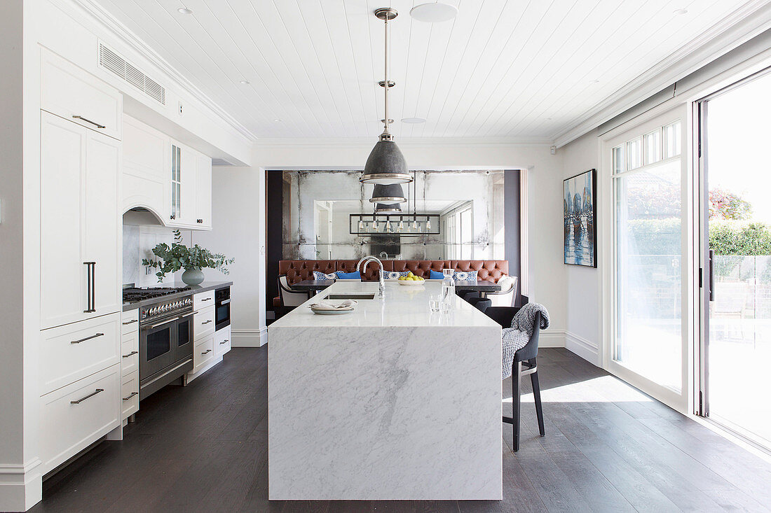 Kitchenette and marble kitchen island in front of patio door in open living room