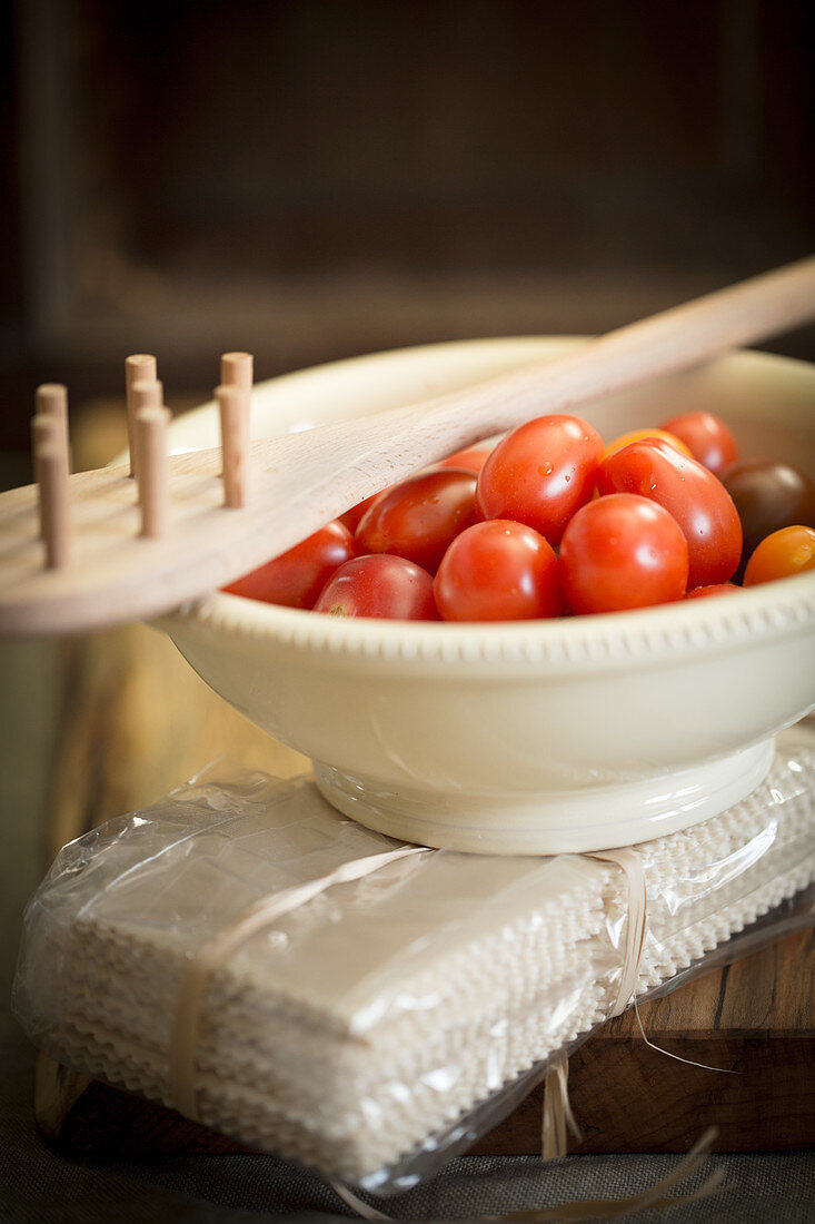 An arrangement of cherry tomatoes, a pasta fork and a pack of pasta