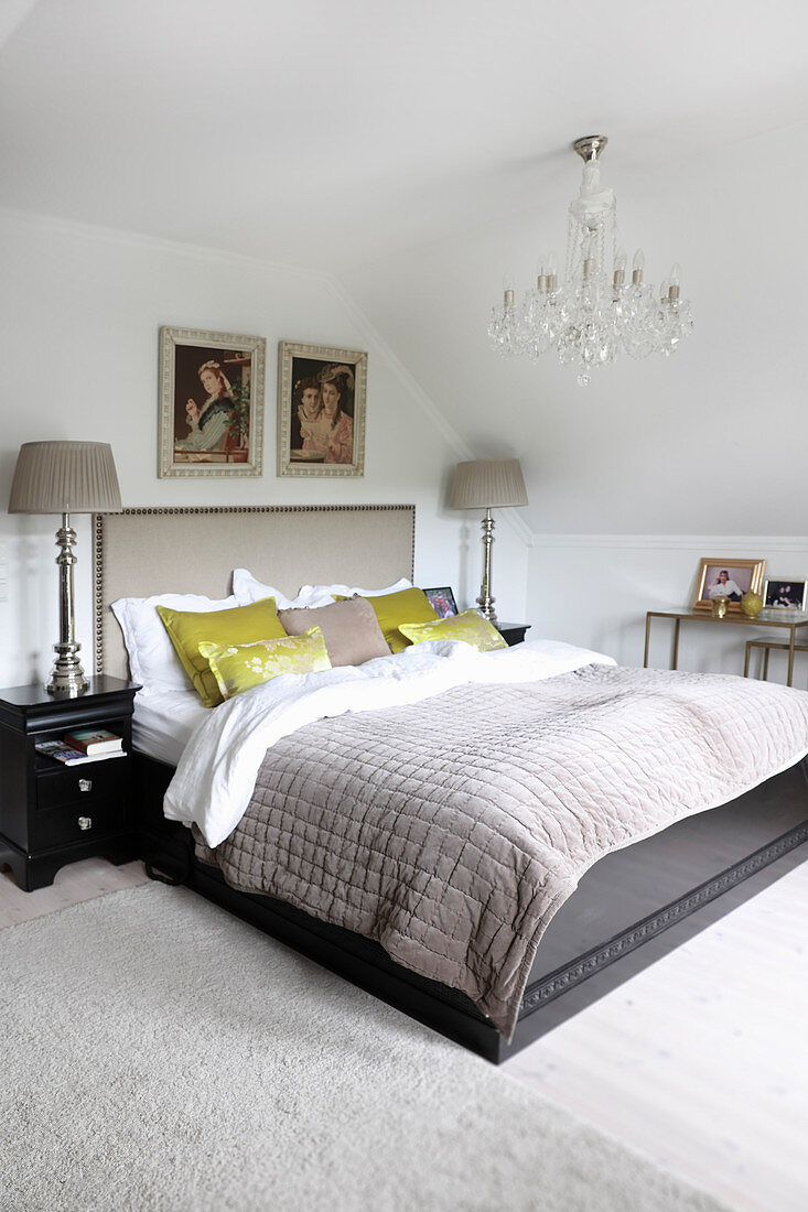 Double bed below chandelier in attic bedroom