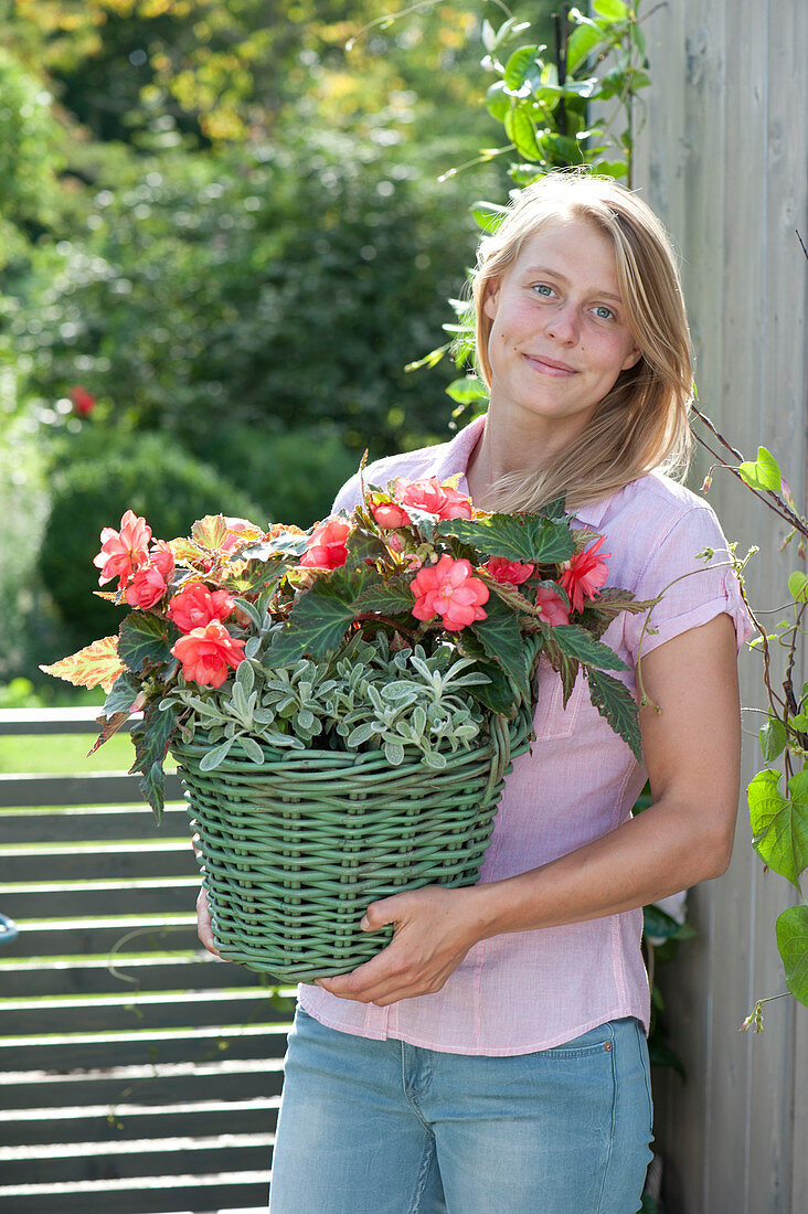 Frau trägt Korb mit Begonia Iconia 'Miss Malibu'