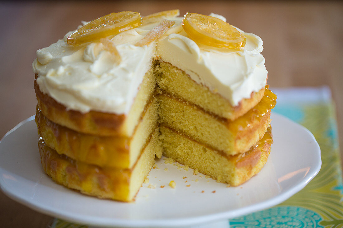 A three-layer lemon cake with frosting and candied lemons
