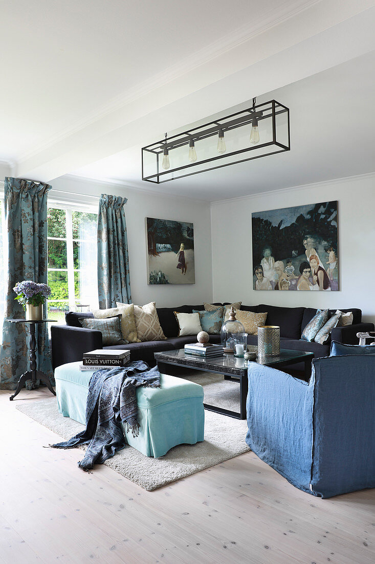 Corner sofa with scatter cushions, coffee table, ottoman and armchair with blue loose cover in living room