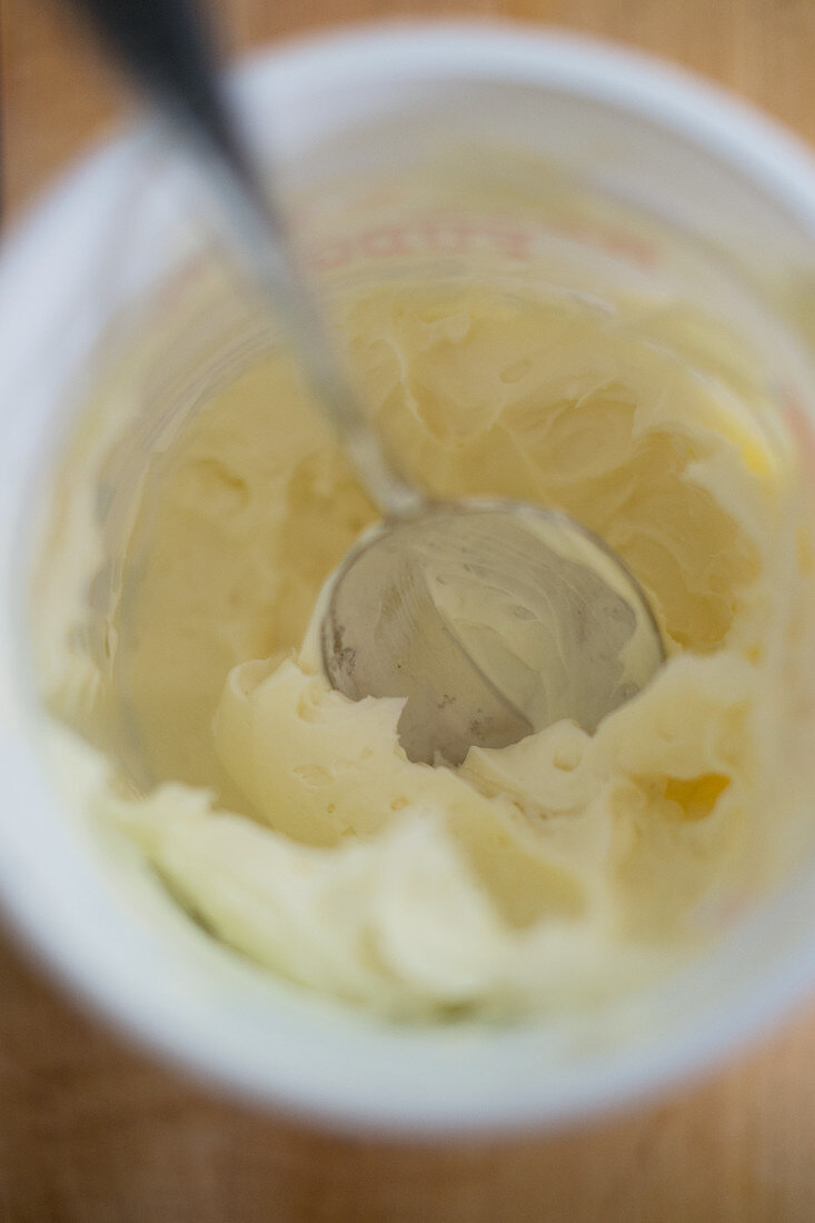 Cream cheese icing in a cup with a spoon