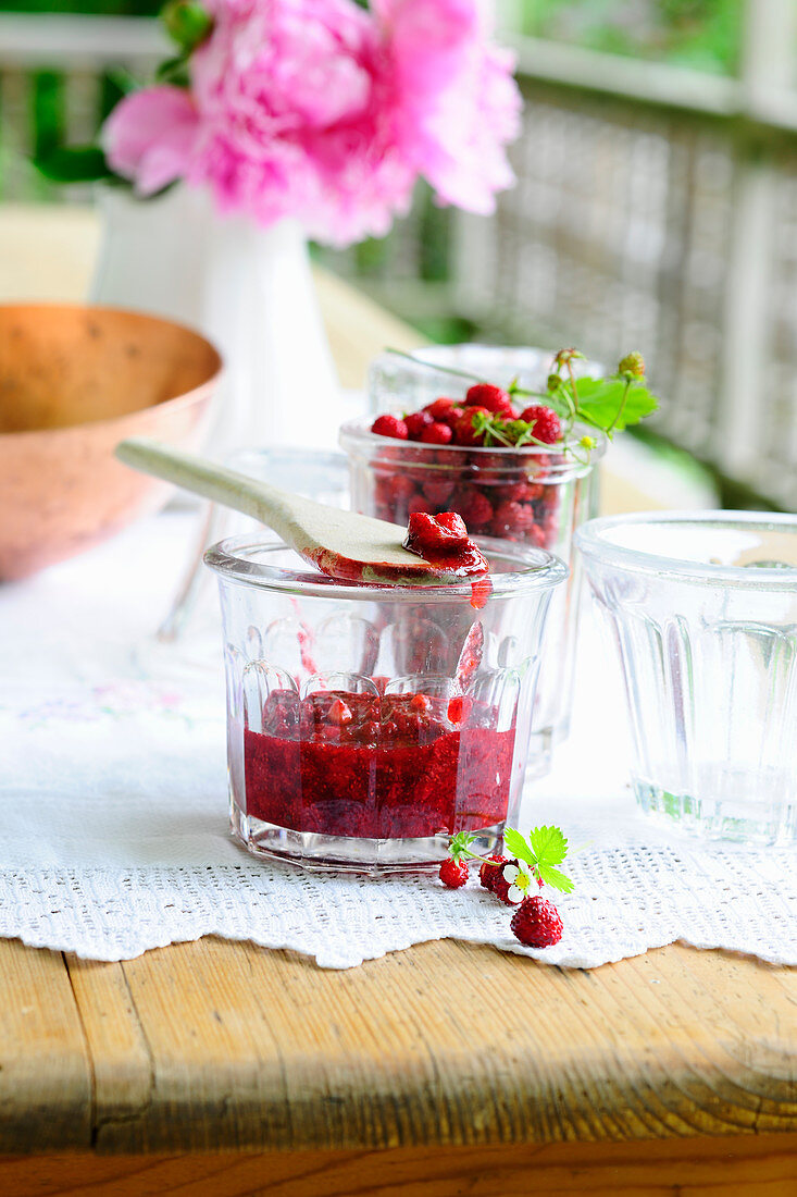 Wild strawberry jam in a glass jar on a summer garden table