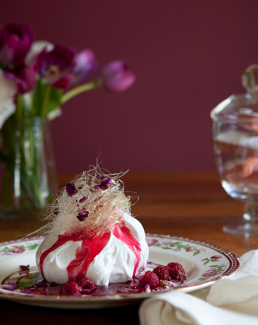 Meringue with toffee 'floss' topping, raspberries and raspberry sauce