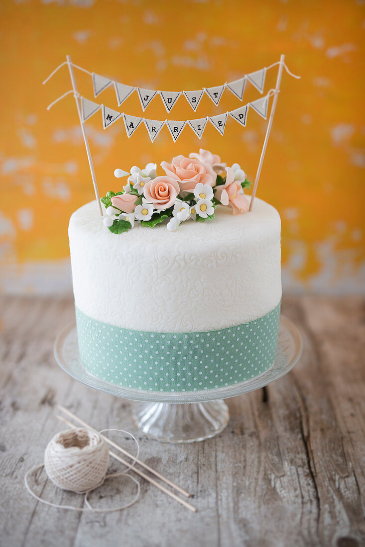 Hochzeitstorte mit Zuckerblumen, Geschenkband und Wimpelkette Just Married