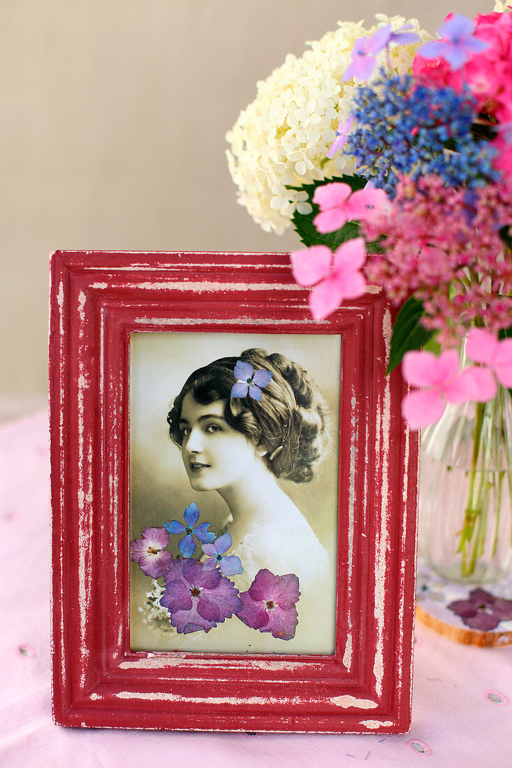 Vintage photo decorated with pressed flowers in red frame