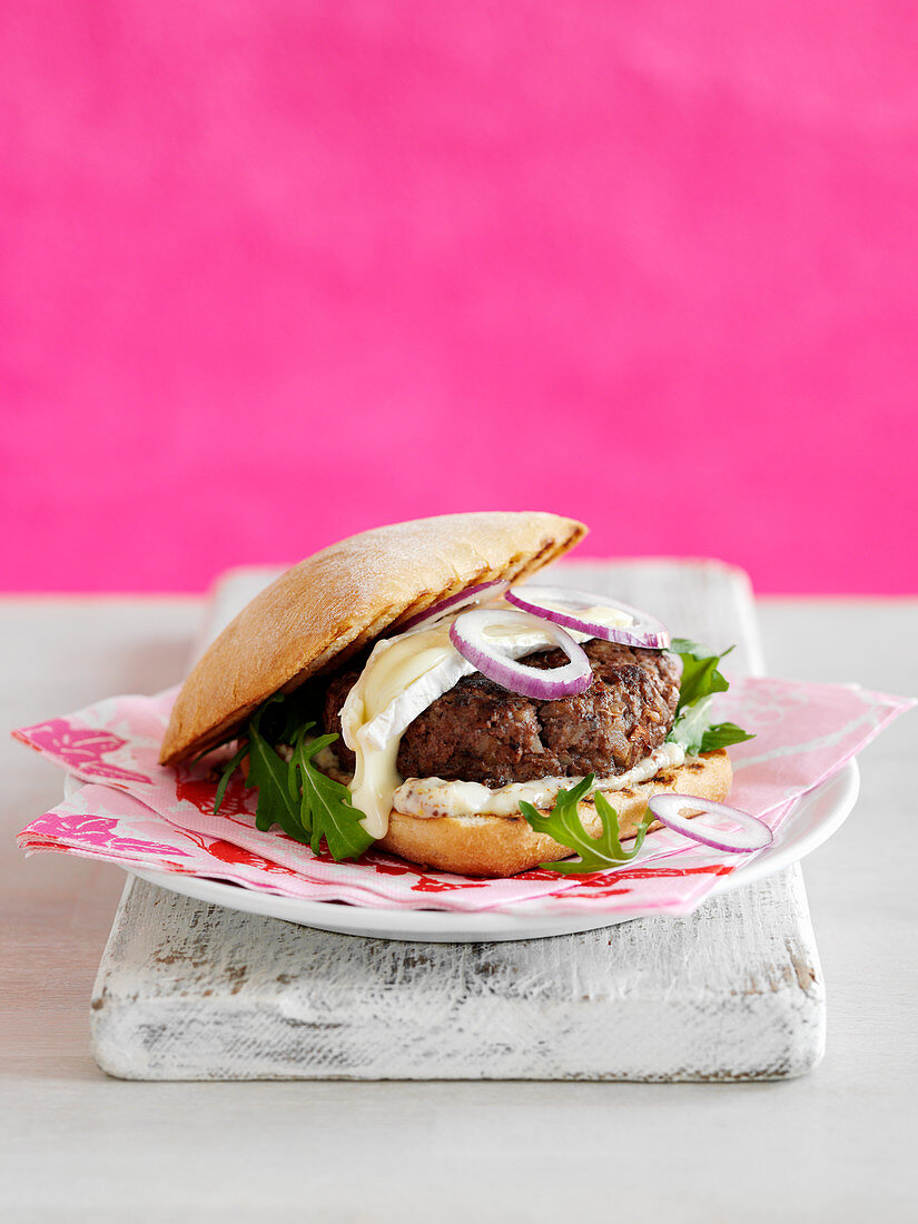 Selbstgemachter Burger auf Teller vor pinkfarbenem Hintergrund