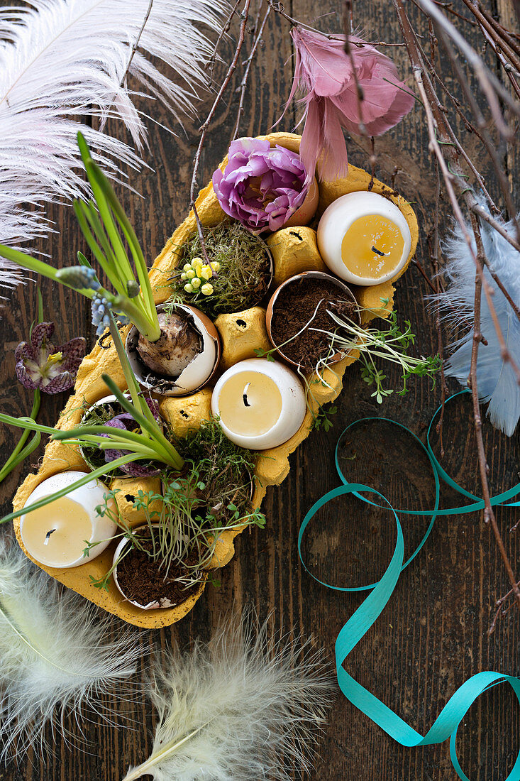 Easter arrangement of egg-shaped candles in eggshells in yellow egg box