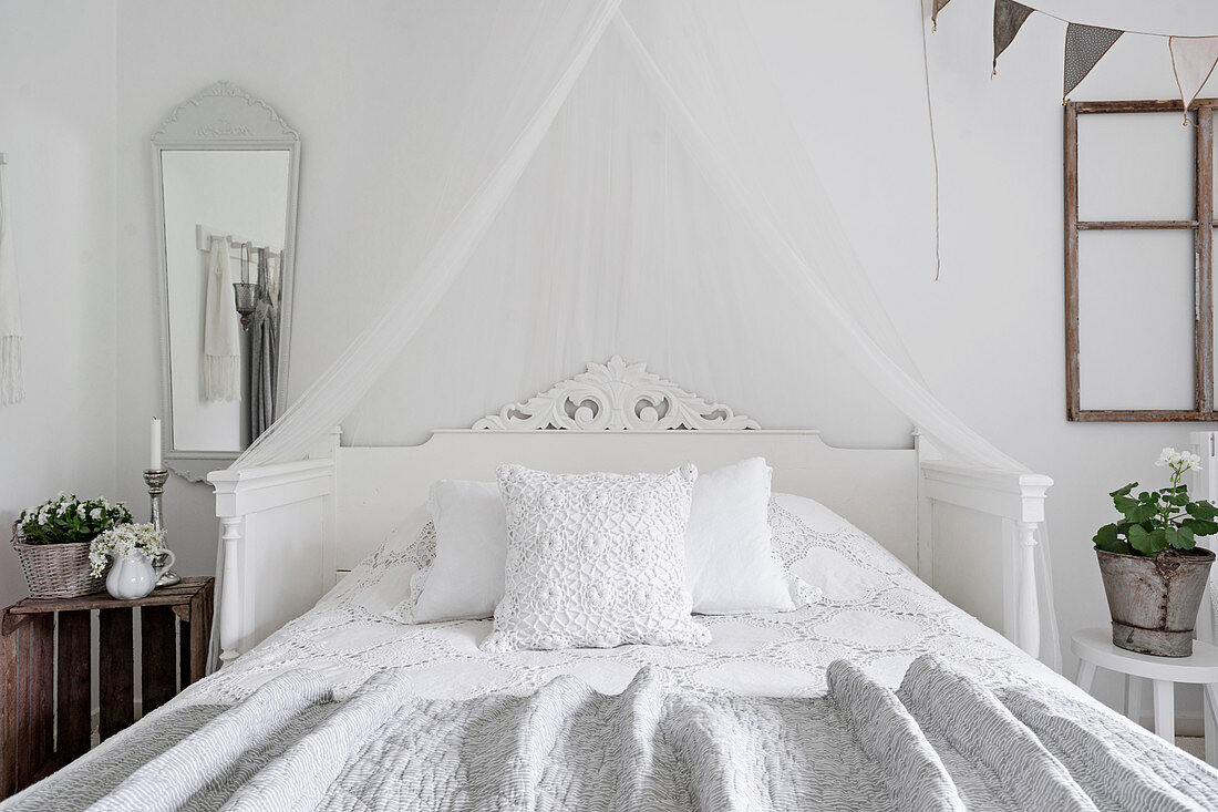 Old ornately carved cot used as headboard of double bed