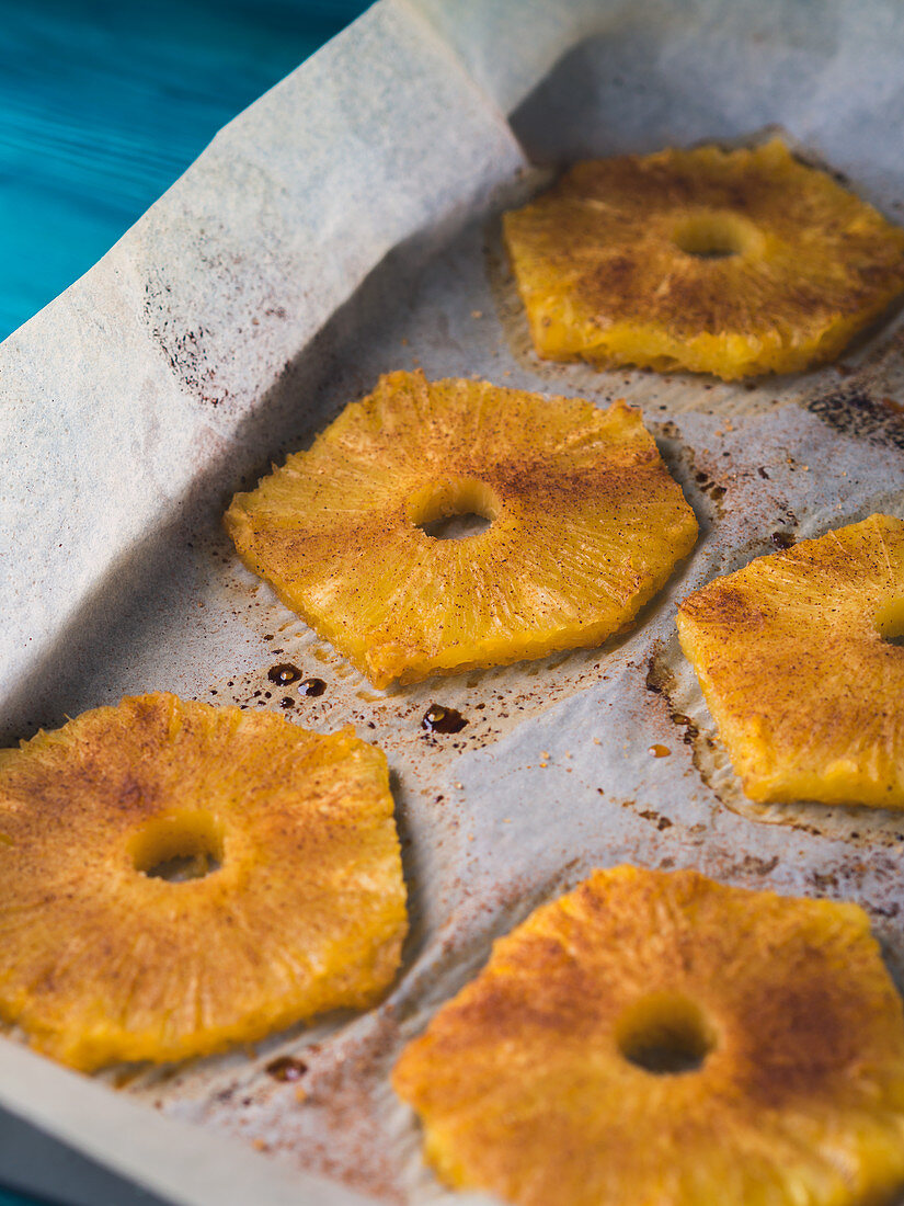 Baked ananas slices with cinnamon, Calvados liqueur and brown sugar on baking tray