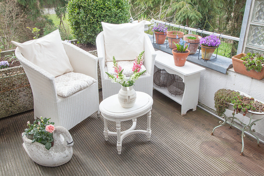 White wicker armchairs and vintage-style coffee table on balcony