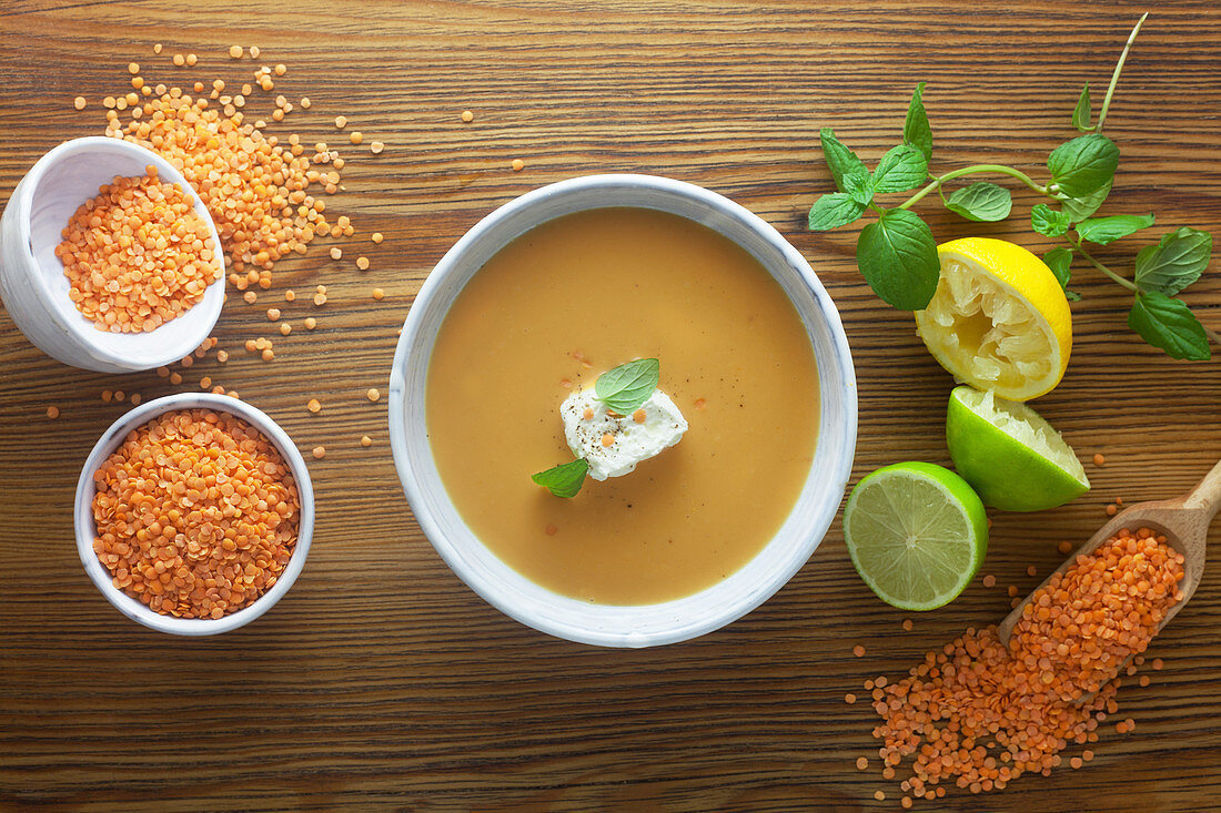 Red lentil soup with ingredients on a wooden surface