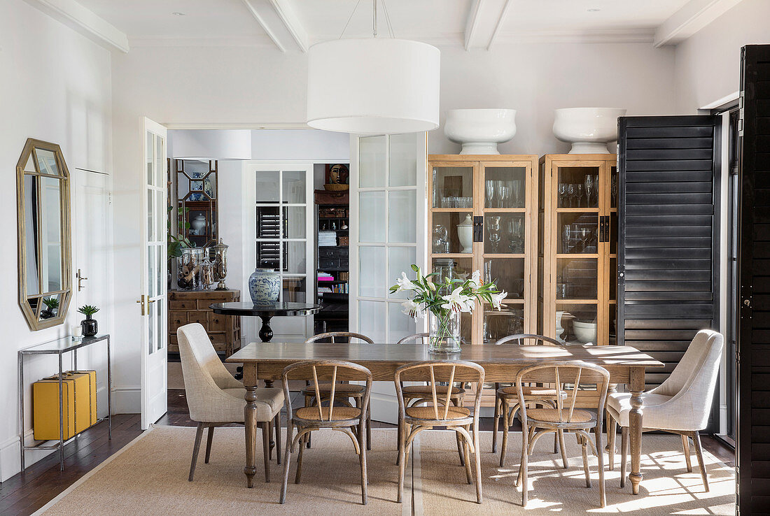 Wooden chair and two upholstered chairs around dining table in front of two display cases