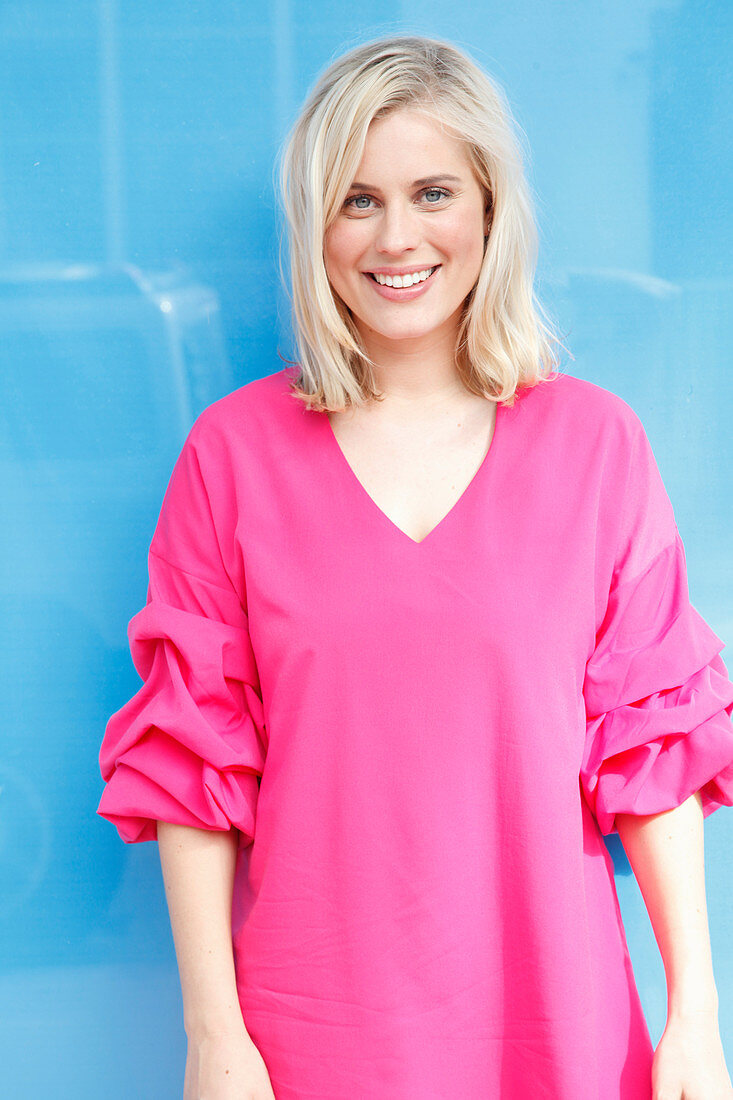 A young blonde woman wearing a long pink top