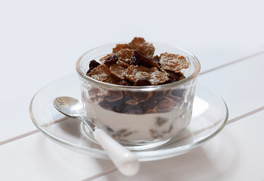 Bowl of Raisin Bran with Milk and Spoon on a White Background