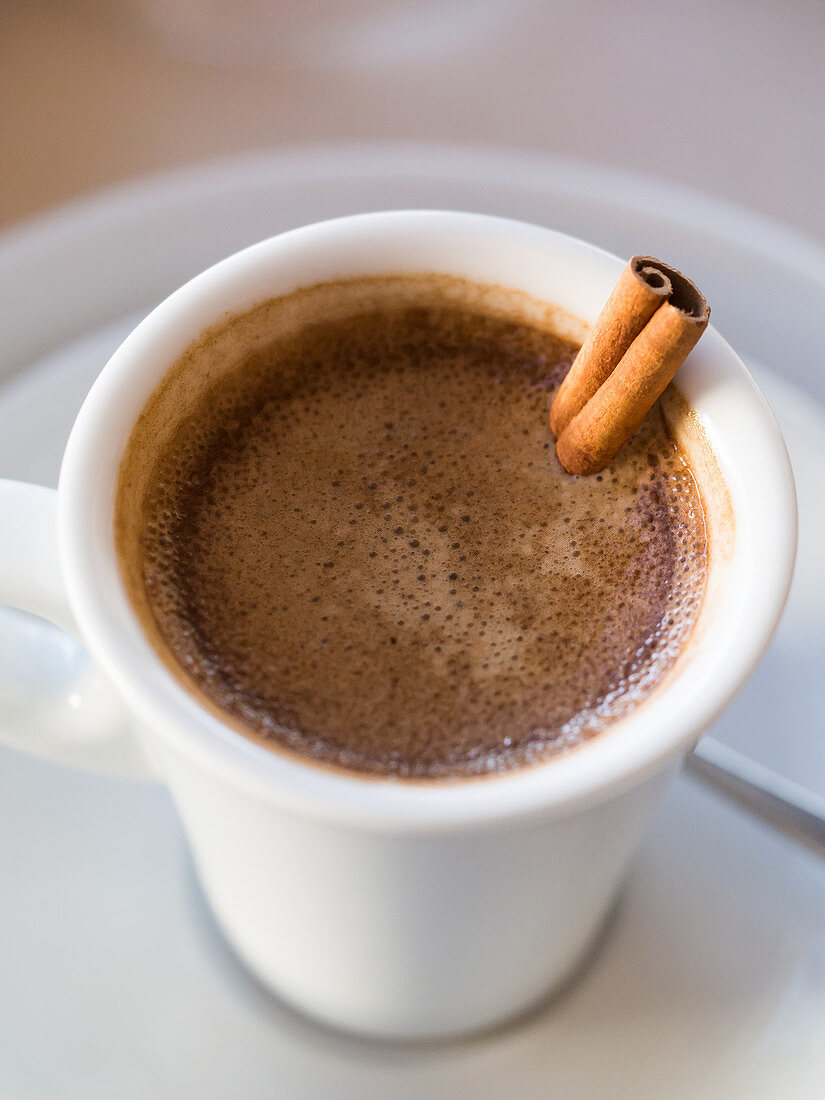 Portugiesischer Kaffee serviert in Tasse mit Zimtstange (Nahaufnahme)