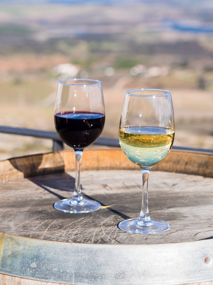 Glasses of red wine and white wine on a wooden barrel (Alentejo, Portugal)