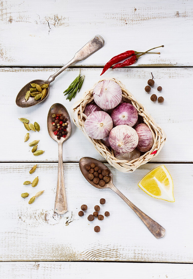 Spices, herbs and garlic on a white wooden surface (seen from above)