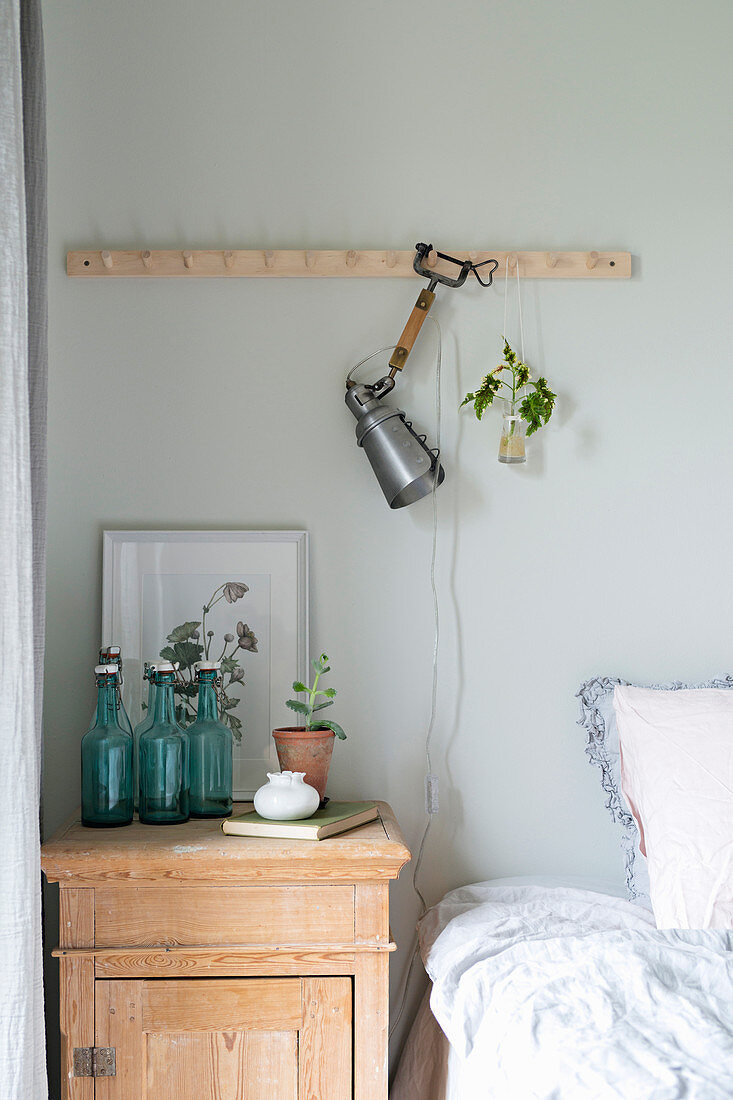 Clip-on lamp on row of pegs above bed and old bedside cabinet