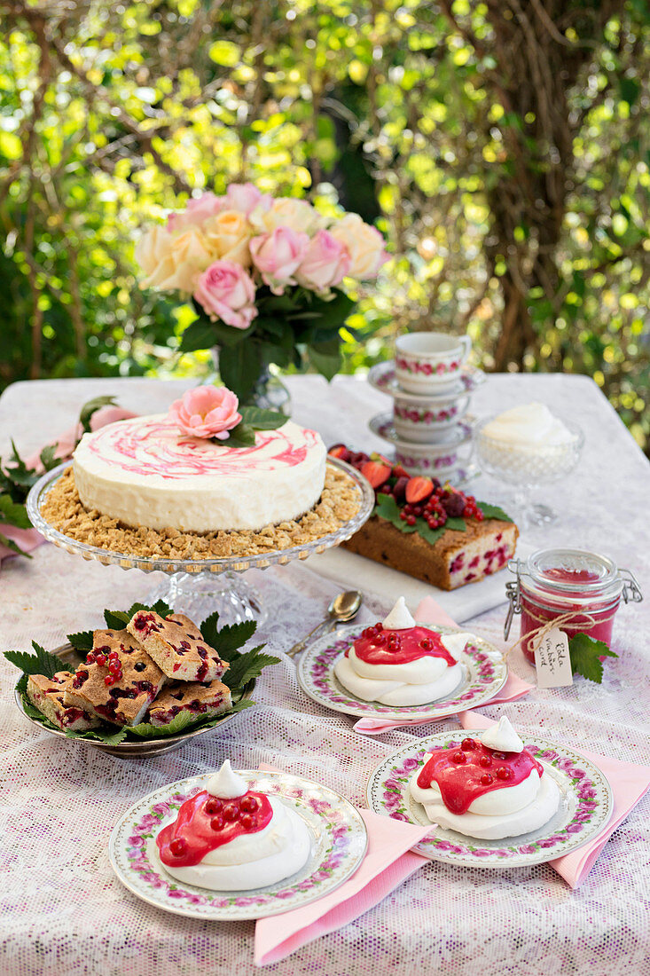 Gedeckter Tisch im Garten mit Johannisbeerkuchen und -desserts