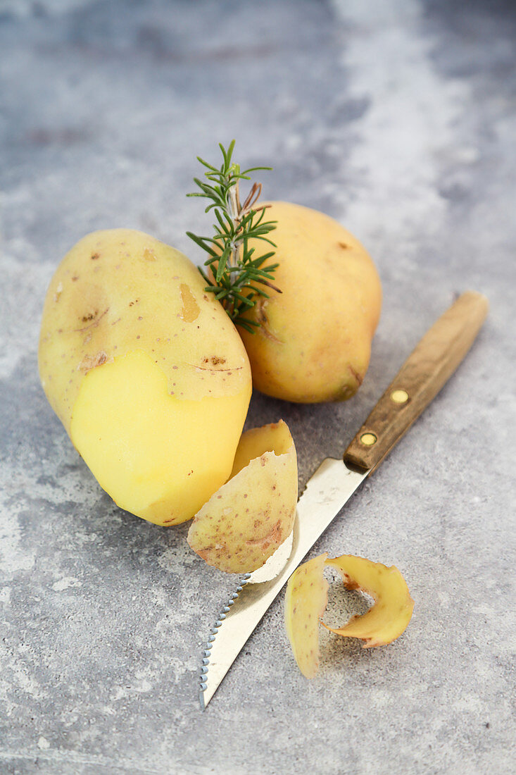 Kartoffeln, teilweise geschält, und Rosmarin