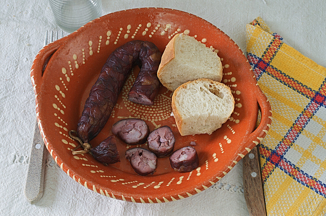 A smoked sausage with bread in a rustic bowl