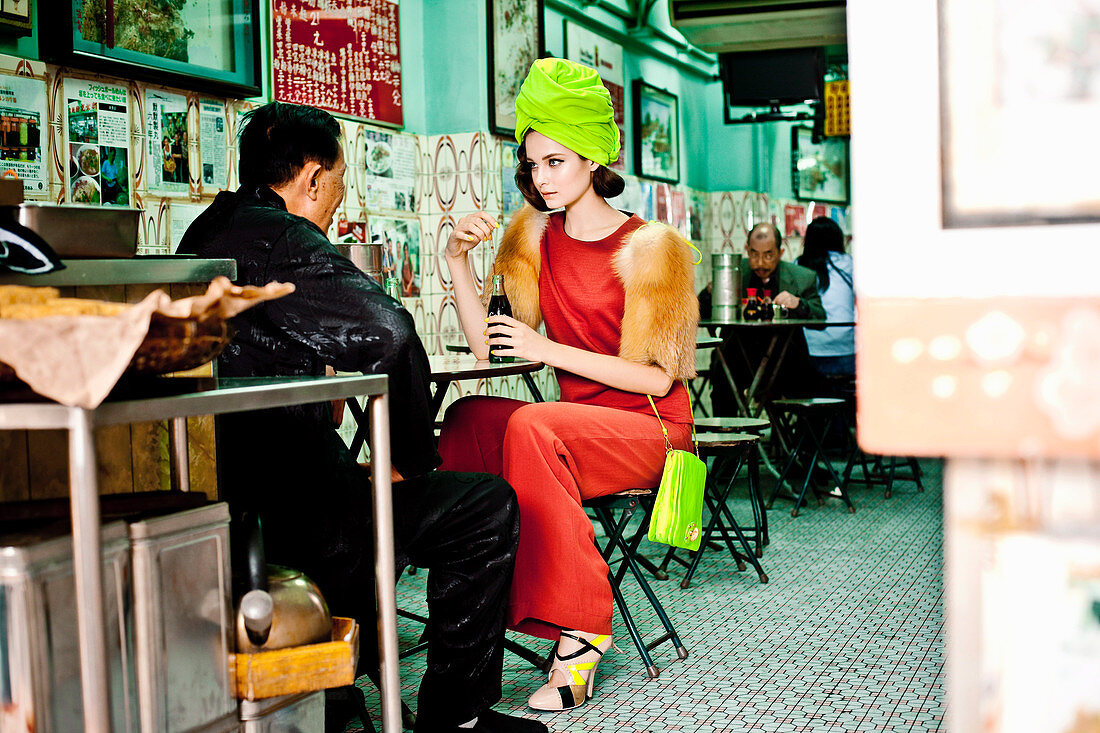 Junge Frau mit neongrünem Turban und rotem Outfit in asiatischem Restaurant